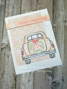 a merry christmas card with an old car and wreath on the front, sitting on a wooden surface