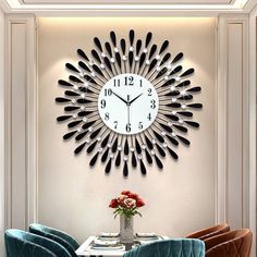 a clock on the wall above a dining room table with blue chairs and a vase filled with flowers