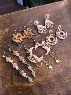 several different types of earrings sitting on top of a wooden table next to each other