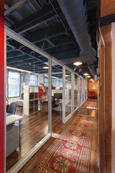 an office with glass walls and wooden flooring on the side of the wall is shown