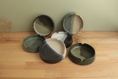 several bowls sitting on top of a wooden table next to a plant in a vase