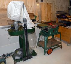 a large green machine sitting inside of a room next to a table and chair with a bag on top of it