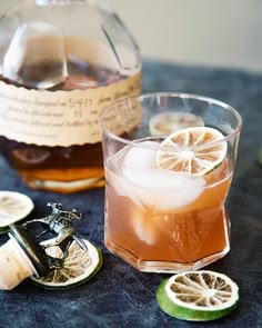 a glass filled with liquid next to sliced lemons