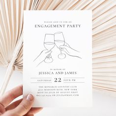 a hand holding up a card that says engagement party with two glasses of wine on it