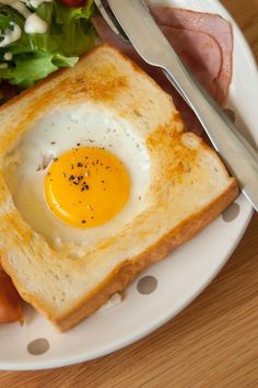 a white plate topped with toast and an egg on top of it next to a salad