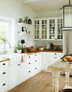 a kitchen filled with lots of white cabinets and counter top next to a wooden table