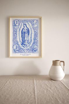 a white vase sitting on top of a table next to a blue and white painting