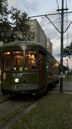 a green trolley car traveling down the street