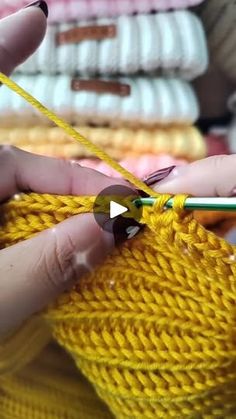 someone is knitting something yellow with a pair of crochet scissors in front of them