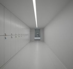 an empty hallway with white walls and lockers