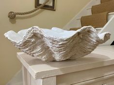 a white bowl sitting on top of a wooden table next to some stairs in a house