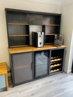 a coffee maker and wine cooler in a room with wood floors, white walls and gray cabinets