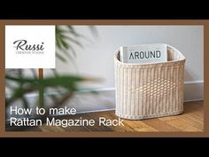 a rattan magazine rack sitting on top of a wooden floor next to a plant