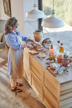 a woman standing in front of a kitchen counter preparing food on top of a cutting board