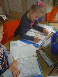 two children sitting at a table with notebooks