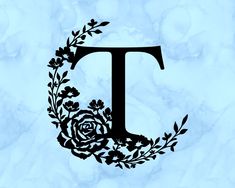 the letter t is surrounded by flowers and leaves on a blue marble slab - stone background