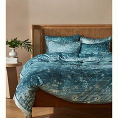 a bed with blue comforters and pillows in a room next to a potted plant