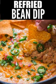 a hand dipping tortilla chips into a bowl of refried bean dip