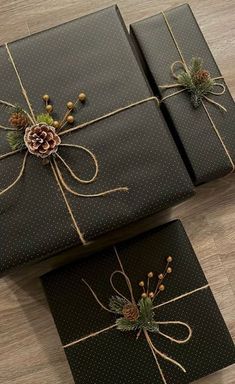 two presents wrapped in black paper and tied with twine, pineconis and evergreen cones