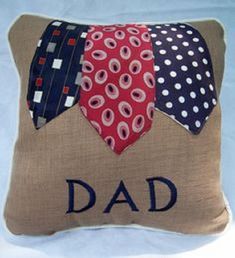 a pillow that says dad on it with ties and polka dots in the middle, sitting on a bed