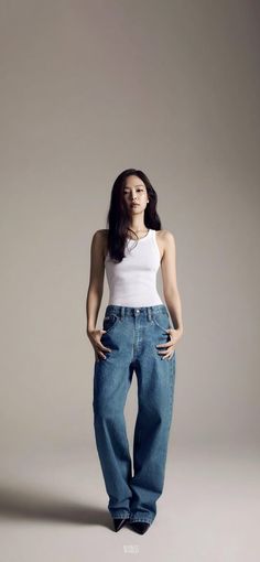 a woman in white tank top and jeans posing for a magazine cover shot with her hands on her hips