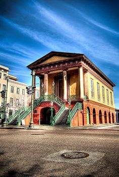 an old building with steps leading up to it's second floor and green railings