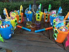 there are many plastic buckets and toothbrushes on the table with other items