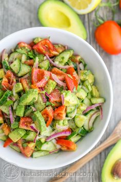 a white bowl filled with cucumber, tomato and onion salad on top of a wooden table