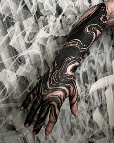 a man's hand with black and white tattoos on it, in front of an abstract background