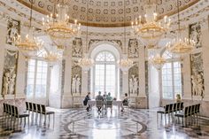 people sitting at tables in the middle of a room with chandeliers