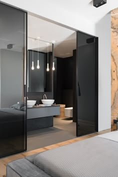 a modern bathroom with black glass doors and stone wall behind the bathtub is seen from across the room