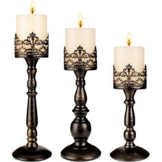 three candles are sitting next to each other on a white background with black filigrees