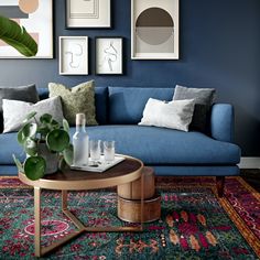 a living room with blue couches and various framed pictures on the wall above it