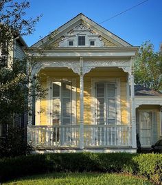 a yellow house with white trim on the front porch