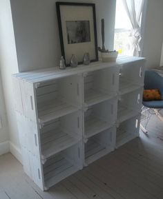 a white bookcase with many shelves and pictures on the top shelf in front of a window