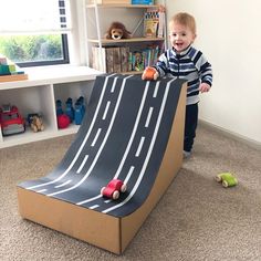 a toddler playing with a cardboard race track