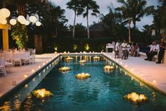 an outdoor wedding with candles floating in the water