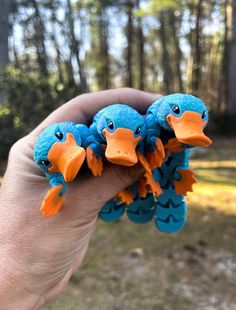 three blue birds with orange beaks are in the palm of someone's hand