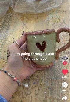 someone is holding a coffee mug with a heart on it and the words i'm going through quite the clay phase