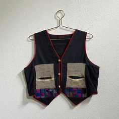 Vintage Rico International black vest featuring red trim, ethnic woven panels on front and back, Net lace pockets, and wood buttons. Made in Thailand. Era: 80s-90s Size: (none Listed, view measurements) (probably a LG) color: Black Material: 100% Cotton  Condition: good vintage- Notable markings/tears: bottom button is chipped, Black color is faded. (view photos) Measurements: (inches) (laying flat) Chest Width: 21" Length: 20.5 Shoulder to shoulder: 14" Sleeve length:  Disclaimer: Vintage items Casual Black Vest With Patchwork, Casual Black Patchwork Vest, Black Cotton Festival Vest, Vintage Black Patchwork Top, Black Folk Style Festival Vest, Traditional Black Vest For Festival, Vintage Black Top For Festival, Lace Pocket, Net Lace