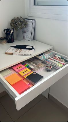 a white desk topped with lots of different types of papers and stationery on top of it