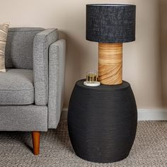 a lamp sitting on top of a wooden table next to a gray couch in a living room