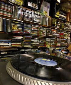 a record player is sitting in front of a wall full of dvds and cds on shelves