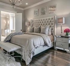 a bedroom with a large bed and chandelier on the ceiling, along with a white rug