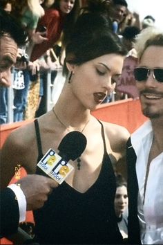 a man and woman standing next to each other in front of a crowd with microphones