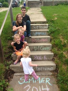 some kids are sitting on the steps with chalk written on them and one child is standing up