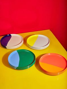 three plates with different colors are on a yellow table