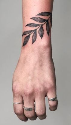 a woman's hand with a black leaf tattoo on it