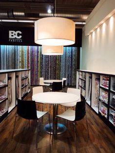 the interior of a clothing store with tables and chairs in front of shelves filled with fabrics