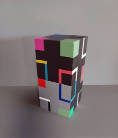 a colorful cube sitting on top of a table next to a gray wall and floor